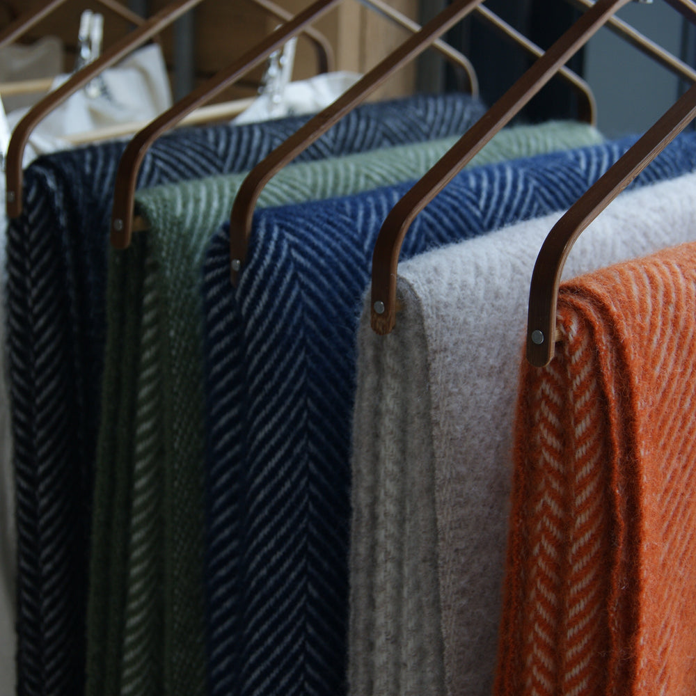 Floks Wool Throws hanging in-store alongside pillows