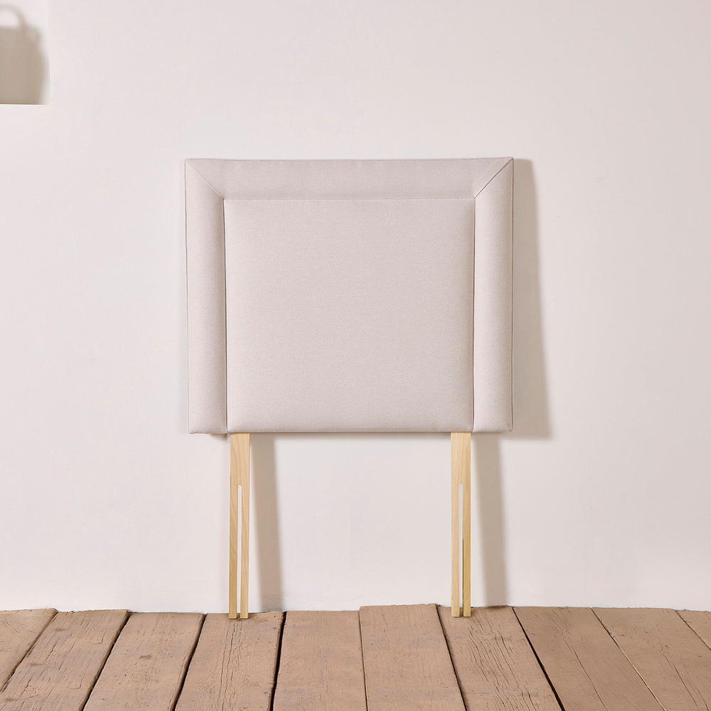 Floks hand upholstered Reykjavik headboard shown in full view, with slatted legs for fixing.  Deep smooth lines create a classical silhouette.