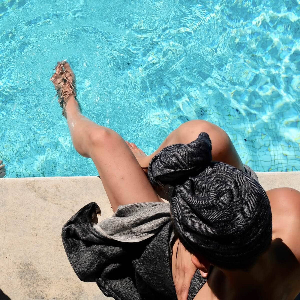 Blästa Henriët Bath Towel and Hair Wrap being used by a person sat by a pool 