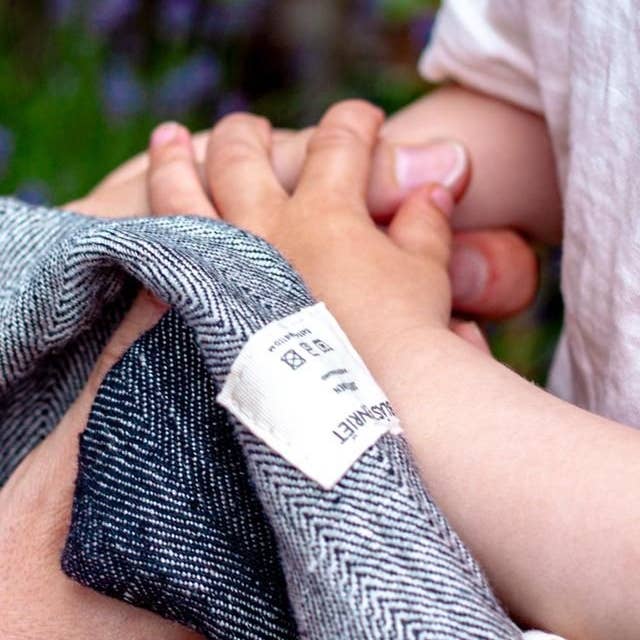 Adult and child hands holding with a Blästa Henriët Towel alongside