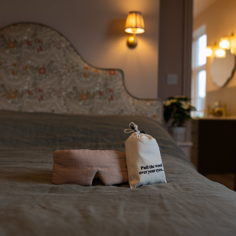 Bed with British Wool filled eye mask and pouch on a bed in a softly lit room