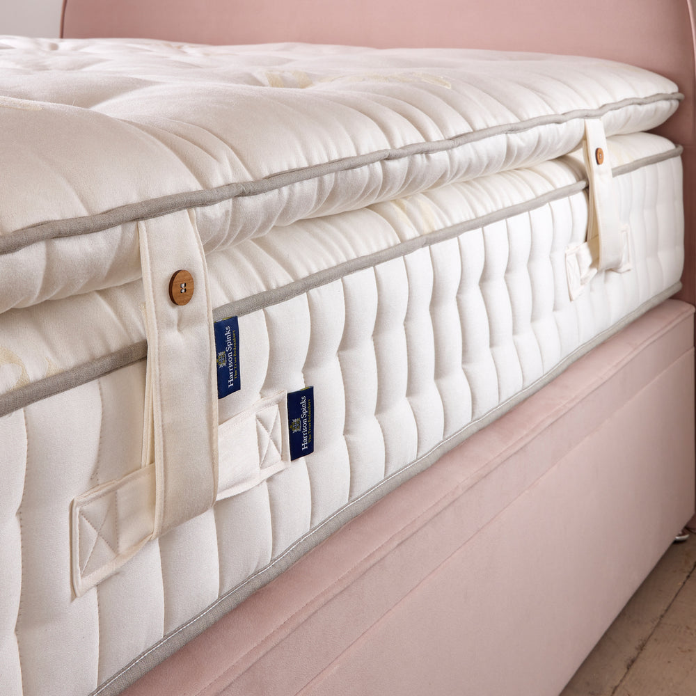 Close up of the side edge, straps and handles of a Floksy Topsy mattress enhancer on a Floks mattress on the pink 'Emily' bed.