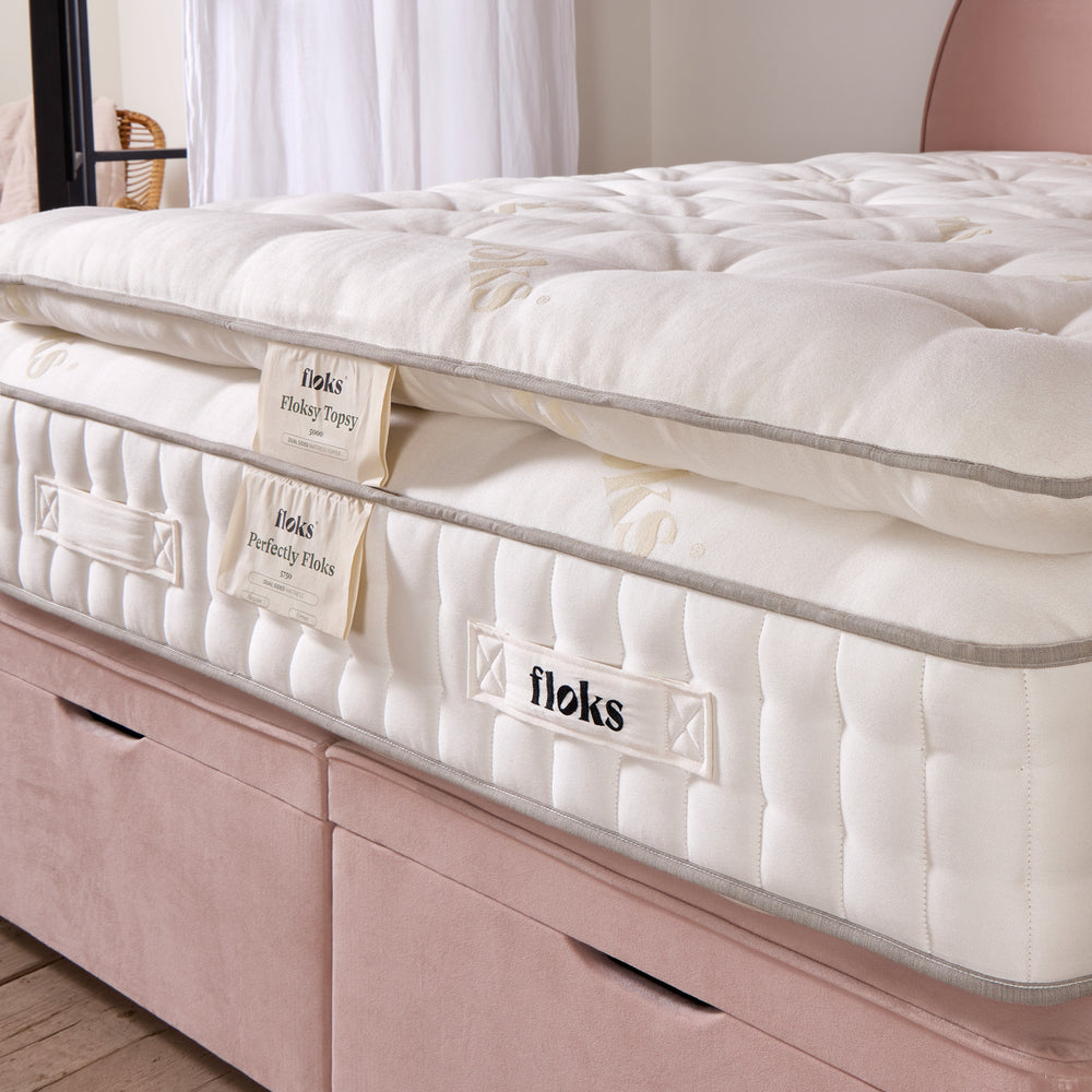 Close up of a Floksy Topsy mattress enhancer on a wooden floor and pink 'Emily' bed.