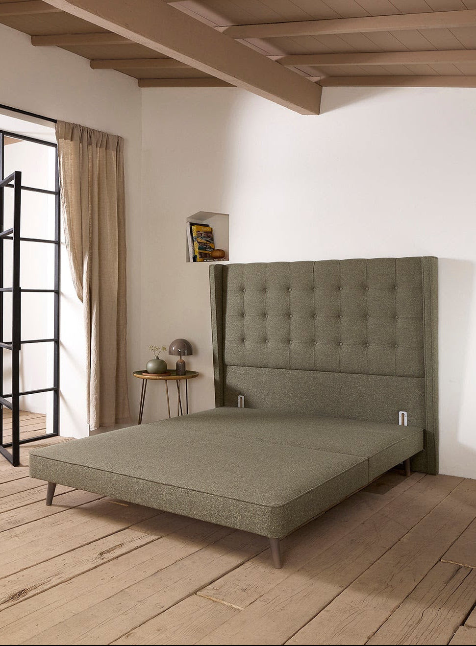 Modern bedroom with a green upholstered bed and wooden flooring.